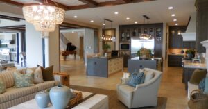 Spacious living room with elegant decor and an open kitchen area, featuring a chandelier and comfortable furnishings.